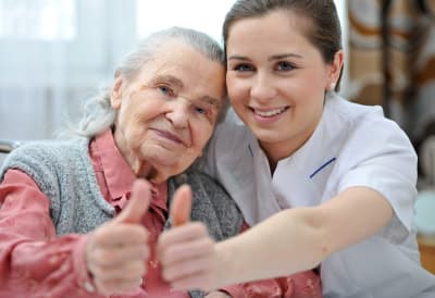 senior woman and her caregiver giving thumbs up